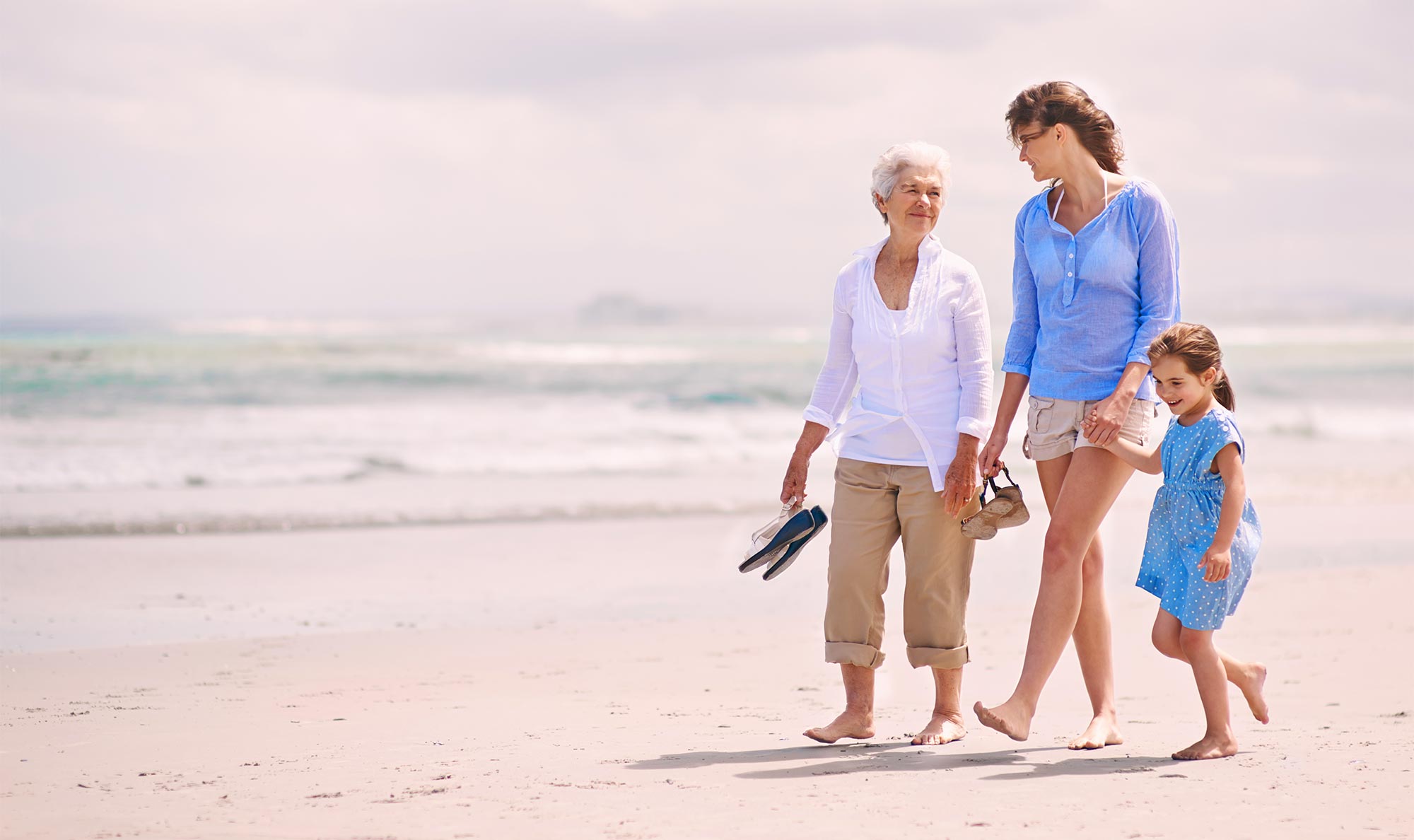 Two women and a girl walking on the beach